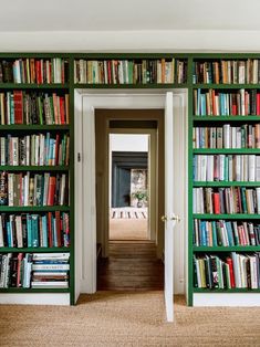 an open door leading to a green bookcase filled with books