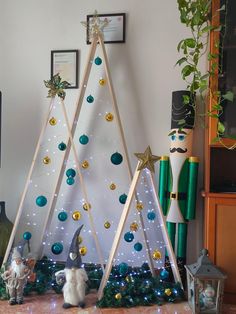 a christmas tree made out of wooden sticks with ornaments on it and two gnomes standing next to it