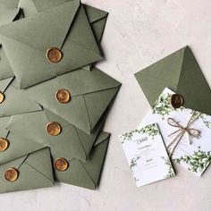 some green envelopes with gold buttons on them and a white card in the middle