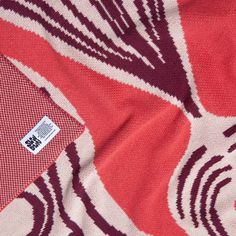 a red and white patterned fabric with a tag on the side that says, ` `