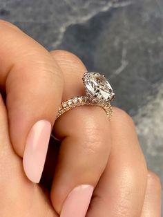 a woman's hand holding a ring with a diamond on it and two diamonds in the middle