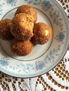 four donuts on a blue and white plate sitting on a doily tablecloth