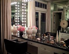 a vanity with lights on it in front of a large mirror and chandelier