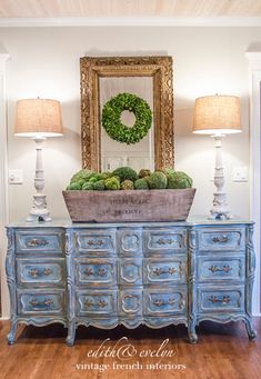 an old dresser with moss on top and a mirror in the corner, next to two lamps