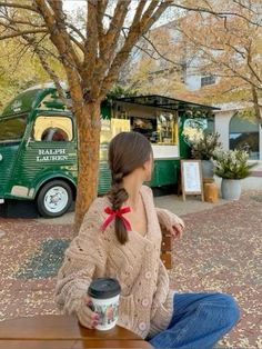 a woman sitting at a table with a coffee cup in front of a food truck