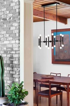 a dining room table with chairs and a cactus in the corner next to an art piece