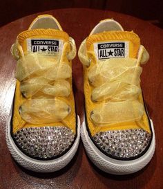 a pair of yellow converse sneakers with bows and diaper on them sitting on top of a wooden table