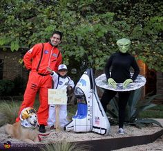 two men and a boy in costumes standing next to an alien man with a dog