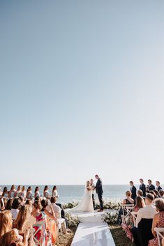 a bride and groom standing at the end of their wedding ceremony in front of an ocean view