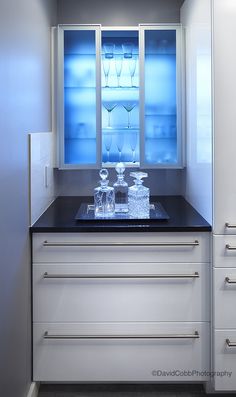 a kitchen counter with two wine glasses on it and an ice chest in the corner