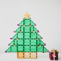 a green plastic christmas tree next to a red present box with gold stars on it