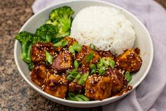 a white bowl filled with meat and broccoli on top of a stone counter