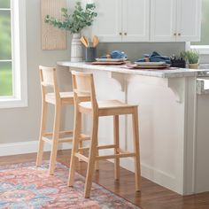 two wooden stools sitting in front of a kitchen counter with plates and utensils on it