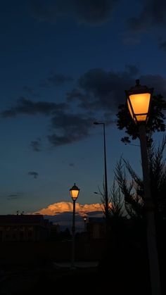 a street light sitting on the side of a road next to a lamp post at night