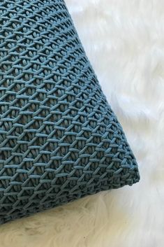 a close up of a blue pillow on a white surface