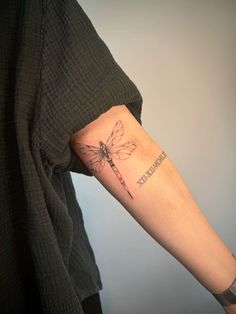 a woman's arm with a dragonfly tattoo on the left side of her arm