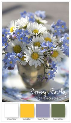 a vase filled with white and blue flowers on top of a table next to a plate