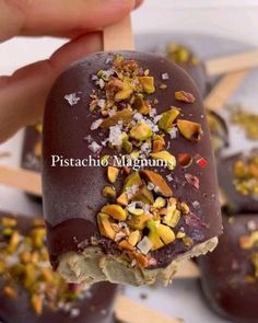 chocolate covered ice cream with nuts and pistachio toppings on a toothpick