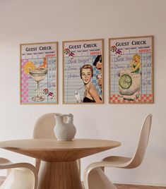 two posters are hanging on the wall above a dining room table with chairs and a vase