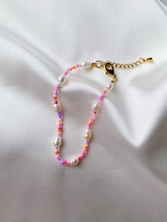 a beaded necklace with pink and white beads on a white satin background, close - up