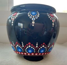 a blue vase with red, white and blue designs on it sitting in front of a window