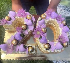 a cake shaped like the number 50 with purple flowers and chocolates on it is being held by someone's hands