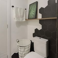 a white toilet sitting in a bathroom next to a black and white tiled wall with shelves above it