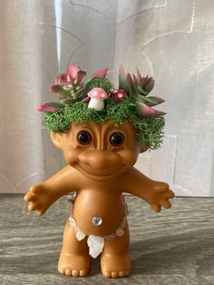 a toy troll with flowers on its head