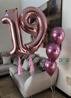 some pink and silver balloons are in the shape of the number twenty nine on a couch