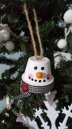 a snowman bell ornament hanging from a christmas tree