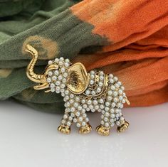 ● Looking for a vintage-style brooch as a perfect gift for her? Introducing our Elephant brooch for good luck, designed with white pearl stones on bronze, is an excellent choice for any occasion. Whether you're looking for a Birthday gift, Mother's Day gift, Bridemaids gift, or a Grandma gift, this brooch is sure to please. ● Our product is a Diplomatic Heritage Collection item that Story Design Store designer Tansel Baybara created in 2013 for the Magnificent Century TV series. The brooch is meticulously crafted by hand, and the stones are handmade by women, making it an exquisite piece of jewelry. ● The elephant represents fertility, family, power and unity. ● Your brooch will arrive in a special package with a velvet box, ensuring that it's ready to gift.      Height : 1.77 inches  (4.5 Bridemaids Gift, Elephant Brooch, Wedding Brooches, Story Design, Bridemaids Gifts, Pearl Stone, Wedding Brooch, For Good Luck, Magnificent Century