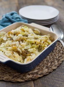 a casserole dish filled with coleslaw on top of a wooden table