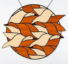 an orange and white stained glass window with birds in the center, hanging from a chain