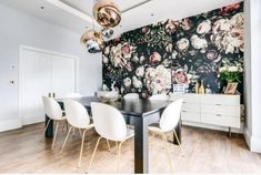 a dining room with floral wallpaper and white chairs in front of a black table