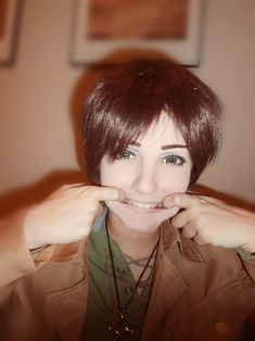 a woman with short brown hair and green shirt smiling at the camera while holding her hands to her mouth