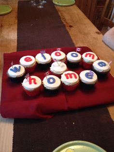 cupcakes are arranged in the shape of letters on a red tablecloth with white frosting