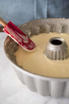 a cake pan filled with batter and a red spatula in the middle of it