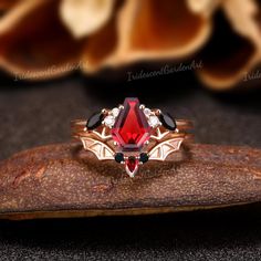 a close up of a ring with a red stone in the middle and black stones on it