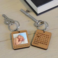 two keychains with a baby's birth photo on them sitting next to a book