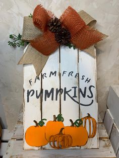 a wooden sign that says farm fresh pumpkins with two small pumpkins on it