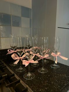 several wine glasses with pink bows are lined up on a counter