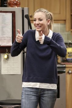 a woman standing in a kitchen giving the thumbs up