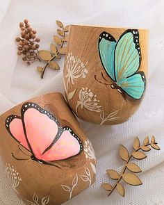 two painted rocks sitting next to each other on a white surface with flowers and leaves