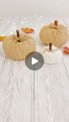 three small pumpkins sitting on top of a white wooden floor next to autumn leaves