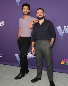 two men standing next to each other in front of a purple wall with the words nbc on it