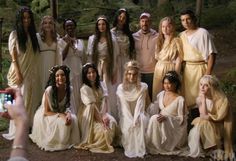 a group of people dressed in ancient greek costumes taking a photo with a cell phone