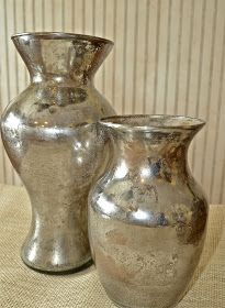 two silver vases sitting on top of a table