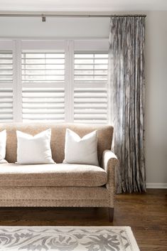 a living room with a couch, rug and window coverings