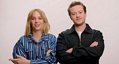 two people standing next to each other in front of a white background with their arms crossed