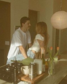 a man and woman standing in front of a stove top oven next to each other